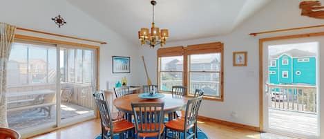 A dining area with a round table, chairs, and a chandelier.