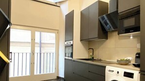 A compact kitchen with a washing machine, a microwave, and a built-in oven.