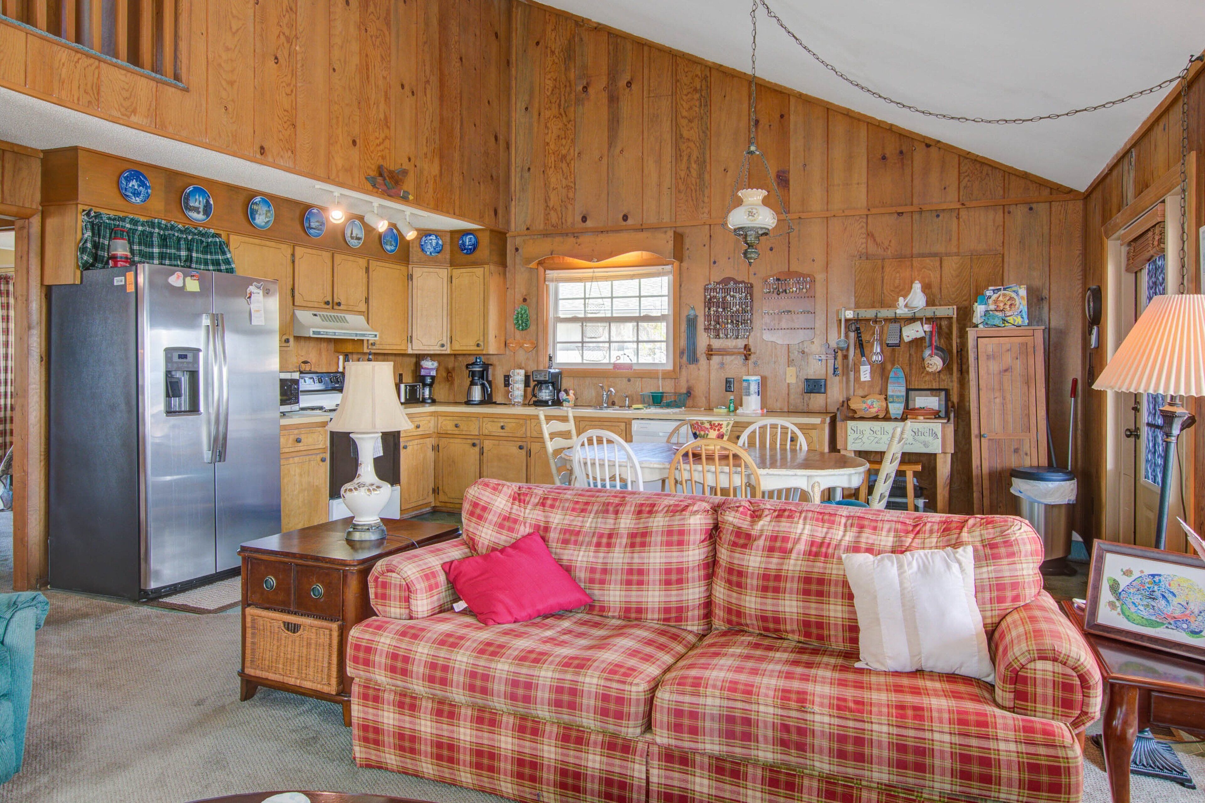 A cozy kitchen with wooden cabinets, a refrigerator, and a plaid sofa.