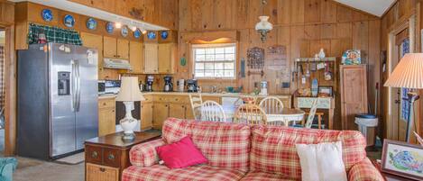 A cozy kitchen with wooden cabinets, a refrigerator, and a plaid sofa.