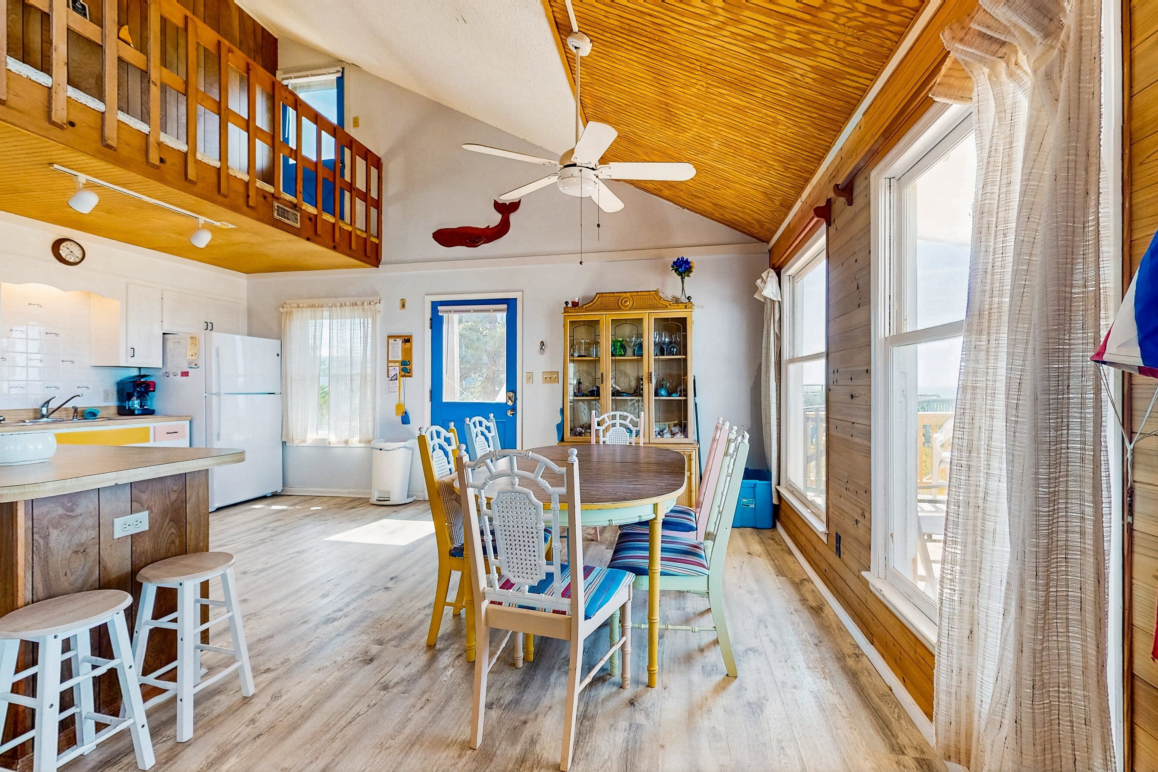 A spacious kitchen with wooden cabinets, a dining area with a wooden table and chairs, and a ceiling fan.