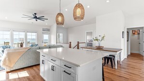 Una cocina amplia con una isla grande, suelo de madera e iluminación colgante.