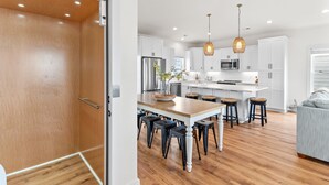 Una cocina moderna con armarios blancos, una isla de madera y taburetes negros.