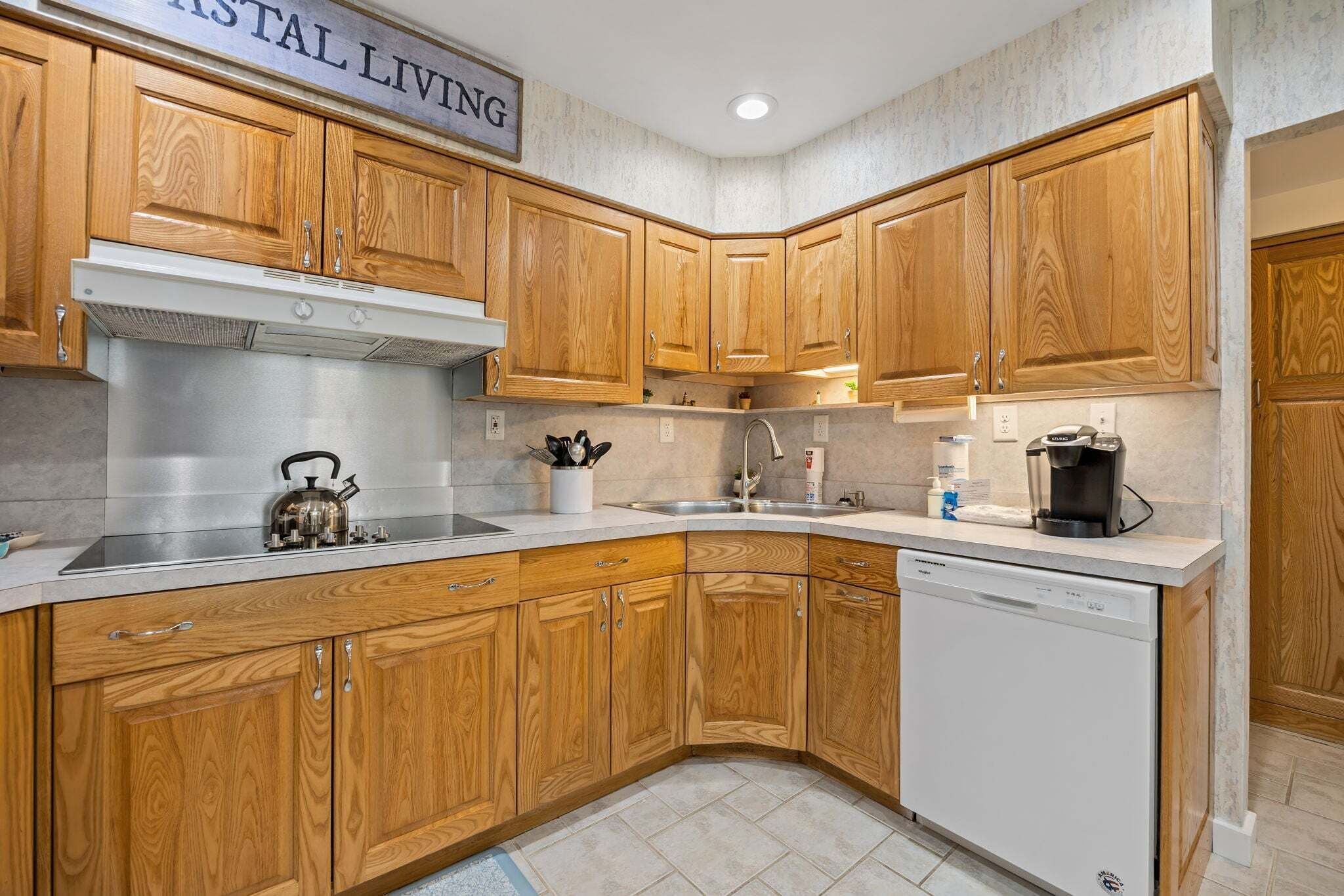 A kitchen with wooden cabinets, a stainless steel range hood, a dishwasher, and a coffee maker.