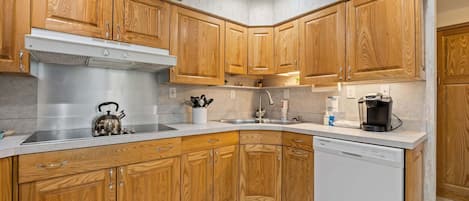 A kitchen with wooden cabinets, a stainless steel range hood, a dishwasher, and a coffee maker.
