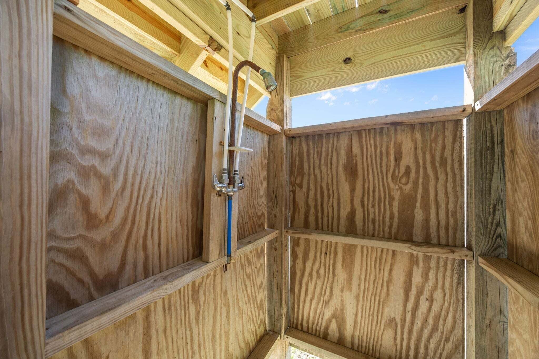 A wooden interior with a metal fixture, wooden beams, and a clear sky view.