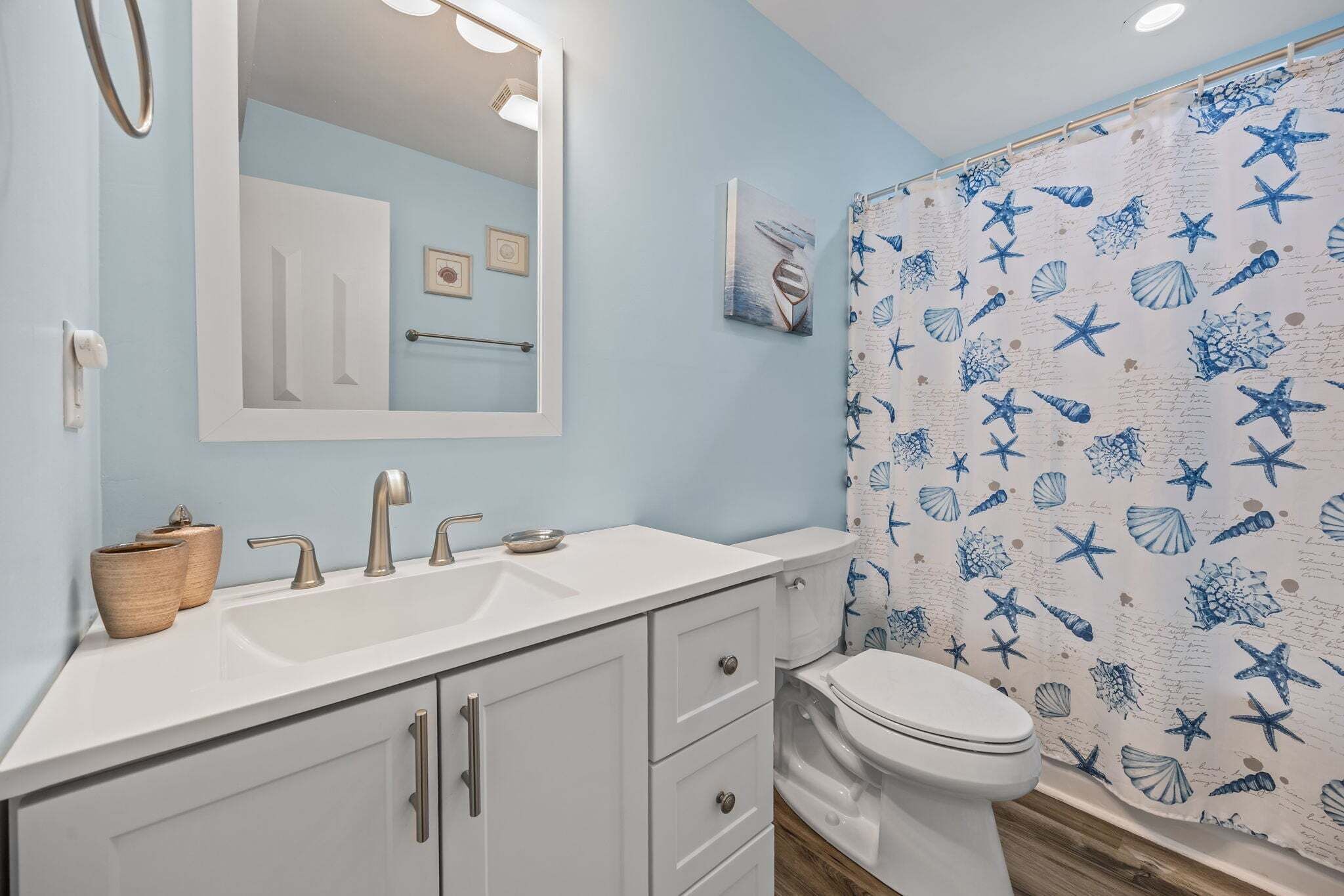A bathroom with a white sink, mirror, and toilet.