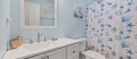 A bathroom with a white sink, mirror, and toilet.