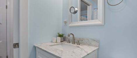 A bathroom with a marble sink, a mirror, a towel ring, and a toilet.