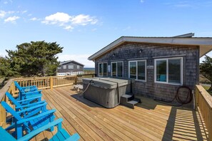 Une terrasse en bois avec des chaises bleues, un jacuzzi et un bâtiment doté de grandes fenêtres.