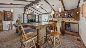A rustic kitchen with wooden beams, a dining area with a large table and chairs, and a visible refrigerator. - Waterfront house w/water views, private hot tub, theater room, game room/bar, AC (Frisco)