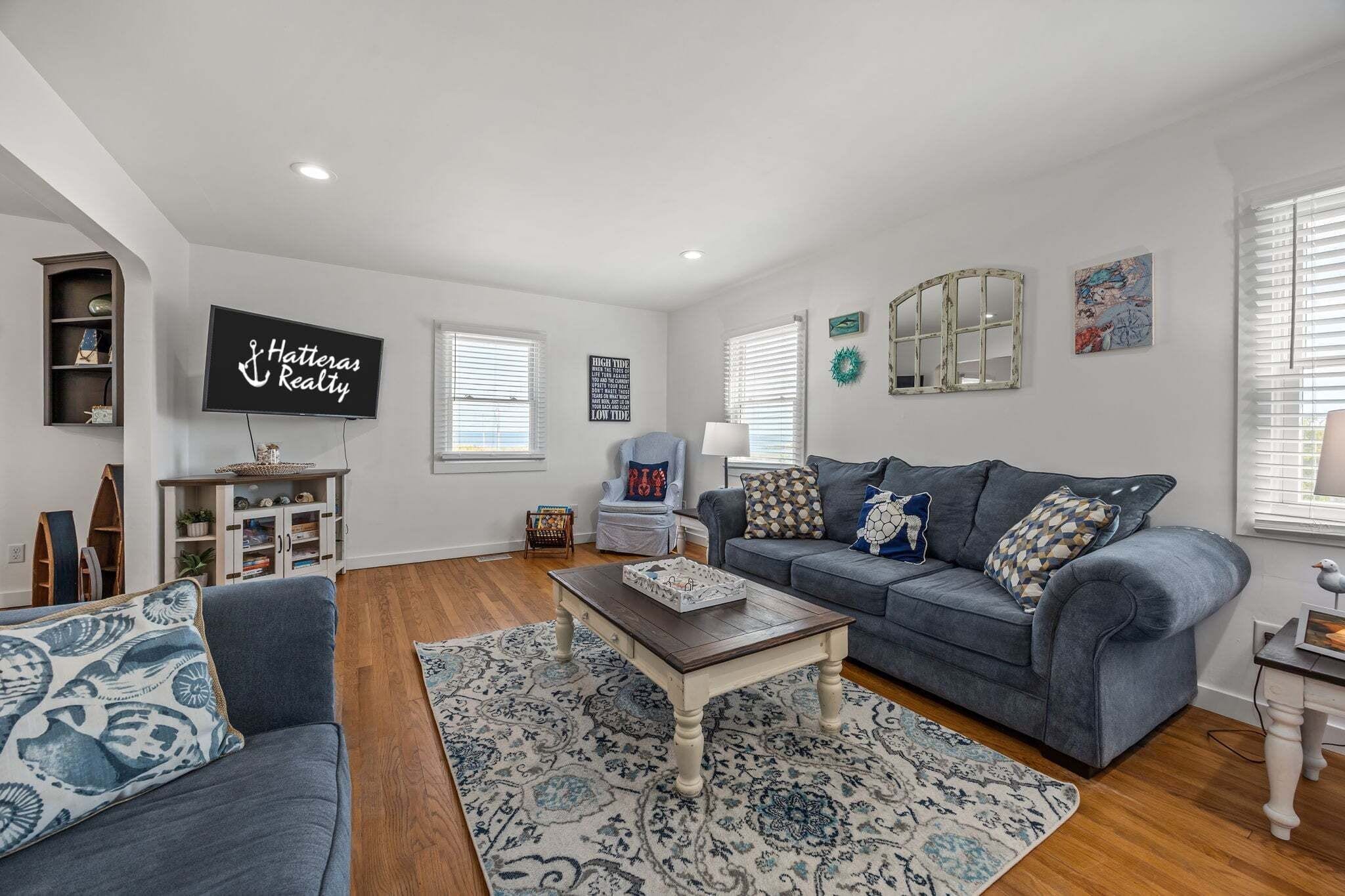 A living room with a grey sofa, a coffee table, and a TV mounted on the wall.