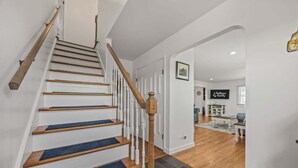 A staircase with wooden steps and a white railing, leading to a room with a white door and a framed picture on the wall. - Waterfront house w/water views, private hot tub, theater room, game room/bar, AC (Frisco)