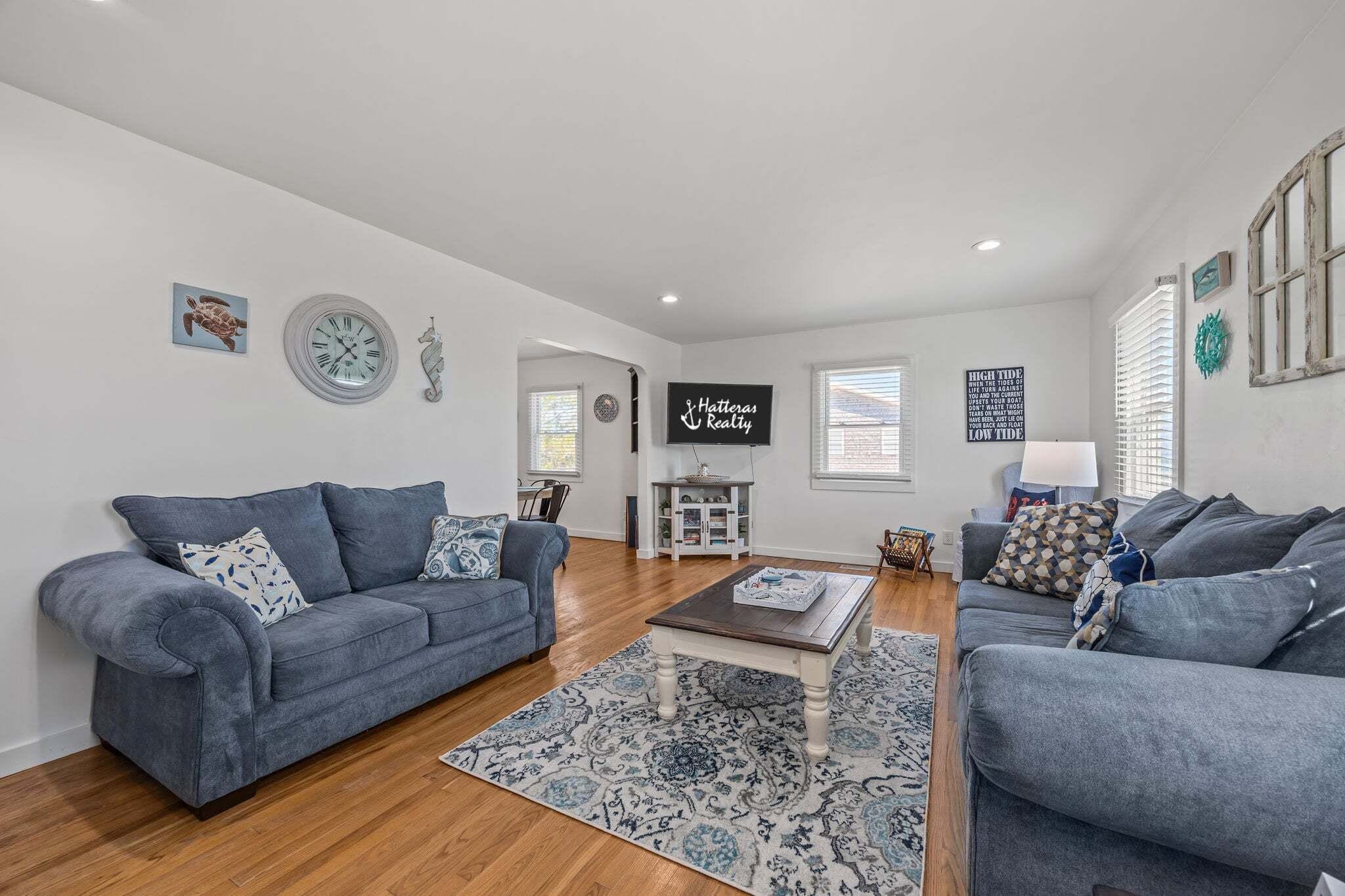 A living room with two grey sofas, a coffee table, a TV, and a decorative wall clock.