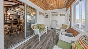 A cozy room with a wooden ceiling, wicker furniture, and a view of the outside. - Waterfront house w/water views, private hot tub, theater room, game room/bar, AC (Frisco)