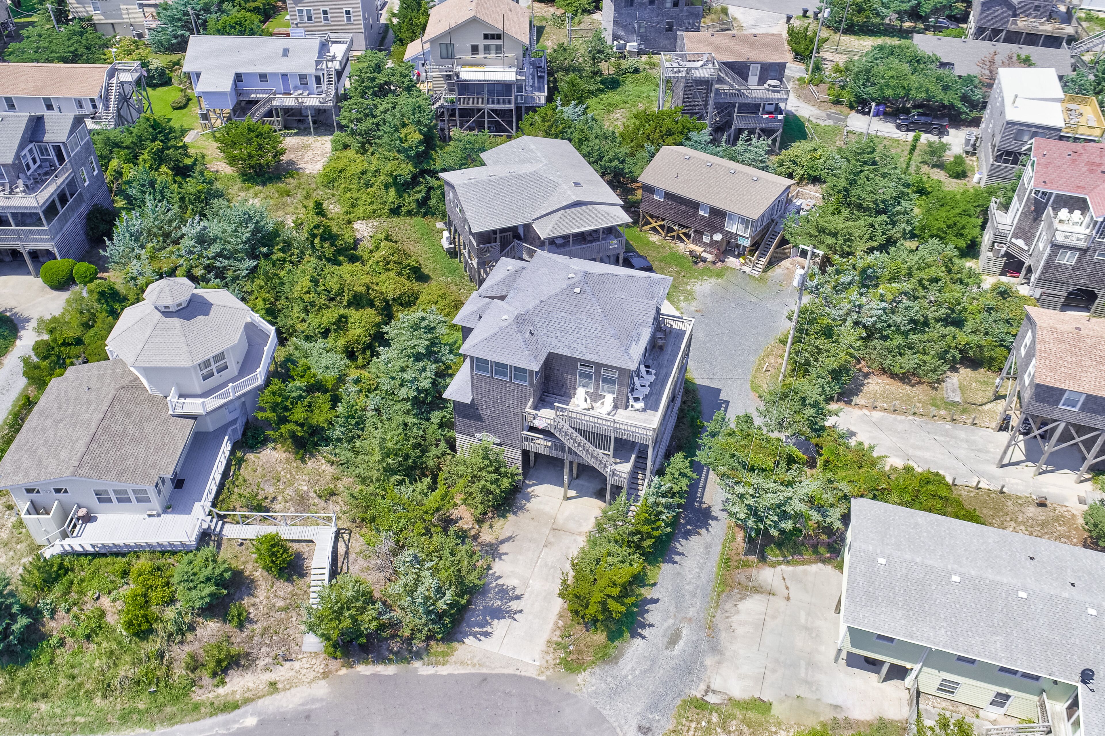 An aerial view of a residential area with houses, including a house with a unique dome-shaped tower and a house with a large deck.