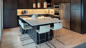 A modern kitchen with a central island, stainless steel appliances, and pendant lighting. - Intracoastal Indulgence: Waterfront, pool, dock and water views! (Holden Beach)