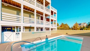 A pool area with a clear blue pool, a white building with multiple balconies, and a sign indicating no trespassing. - Beautiful house with private pool, hot tub, central AC, & washer/dryer (Salvo)