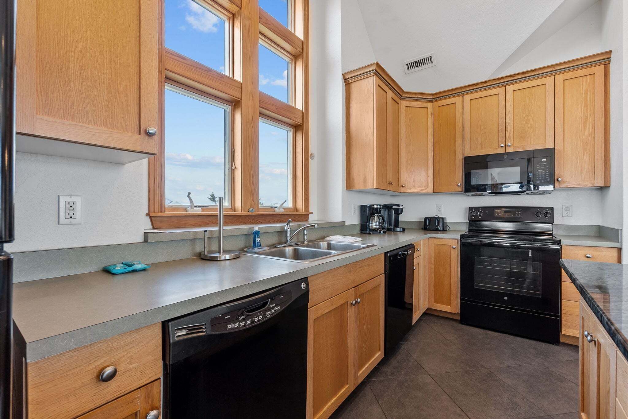 A kitchen with wooden cabinets, a dishwasher, a stove, and a microwave.