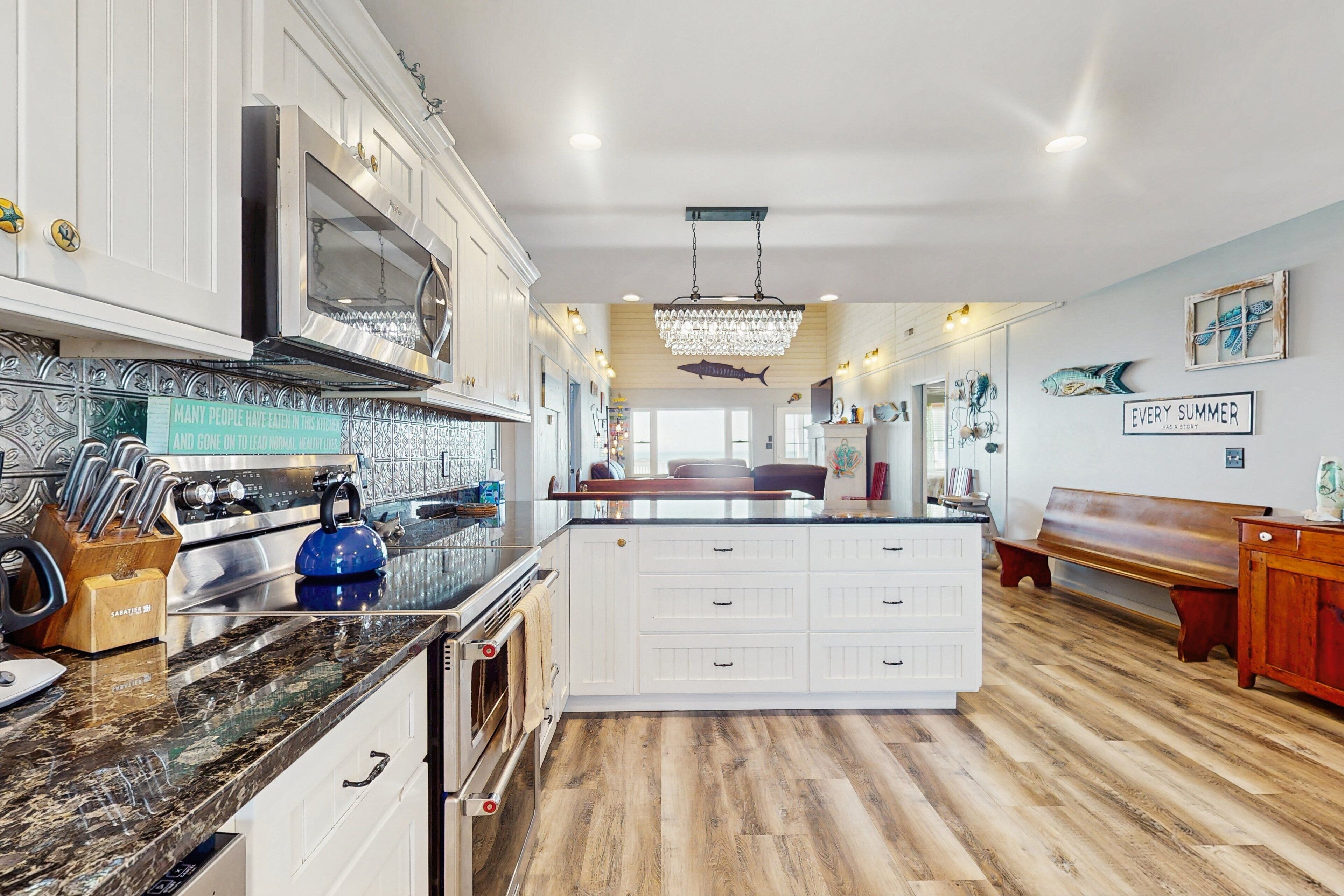 A spacious kitchen with a central island, white cabinetry, and a wooden floor.