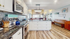 A spacious kitchen with white cabinetry, a central island, and a wooden floor.