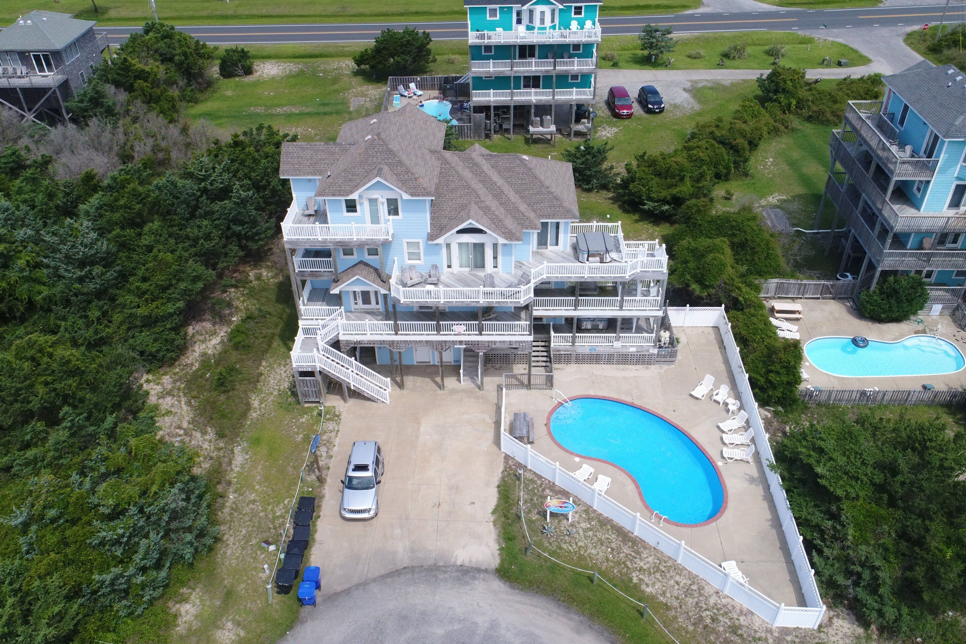A large house with a swimming pool, multiple decks, and a garage.