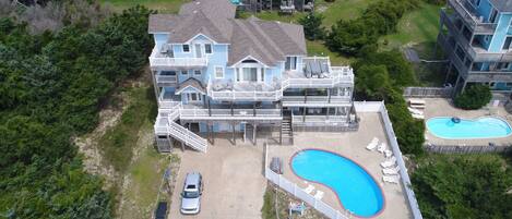 A large house with a swimming pool, multiple decks, and a garage.