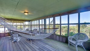 A wooden deck with a hammock and wicker chairs, large windows with a view of greenery. - Oyster Cove 341: Cove-front, rooftop deck w/views, boat dock (Avon)
