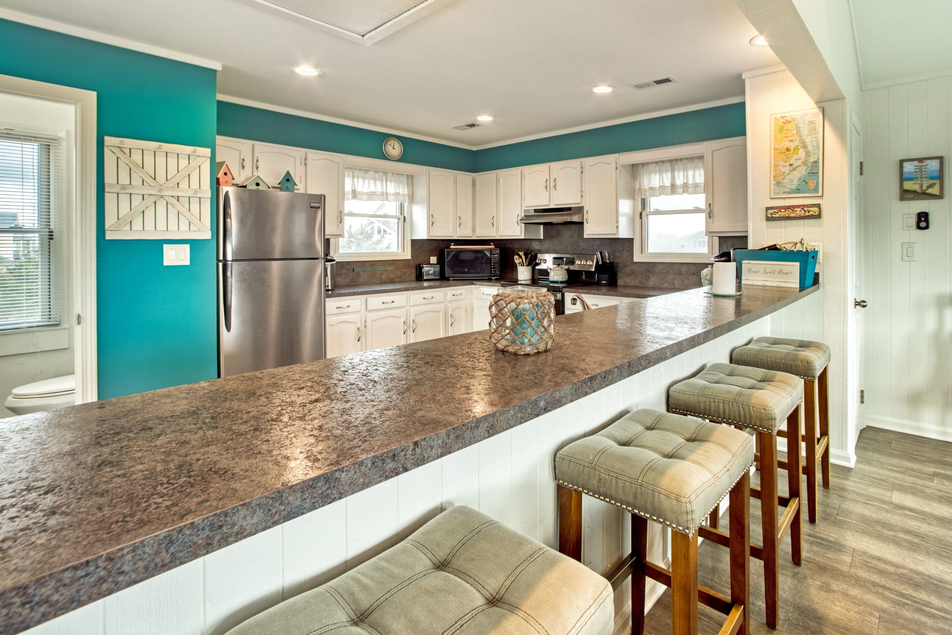 A modern kitchen with a granite countertop, stainless steel appliances, and bar stools.