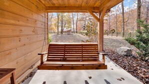 A wooden bench under a covered area with a view of a forested area. - Free Ruby Falls Ticket & More -Hot tub-3 acres-5 min walk to lake fishing-15 min Cloudland Canyon (Rising Fawn)