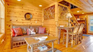 Interior acogedor de una cabaña de troncos con un sofá de madera, una mesa de centro rústica y un comedor con sillas de madera.