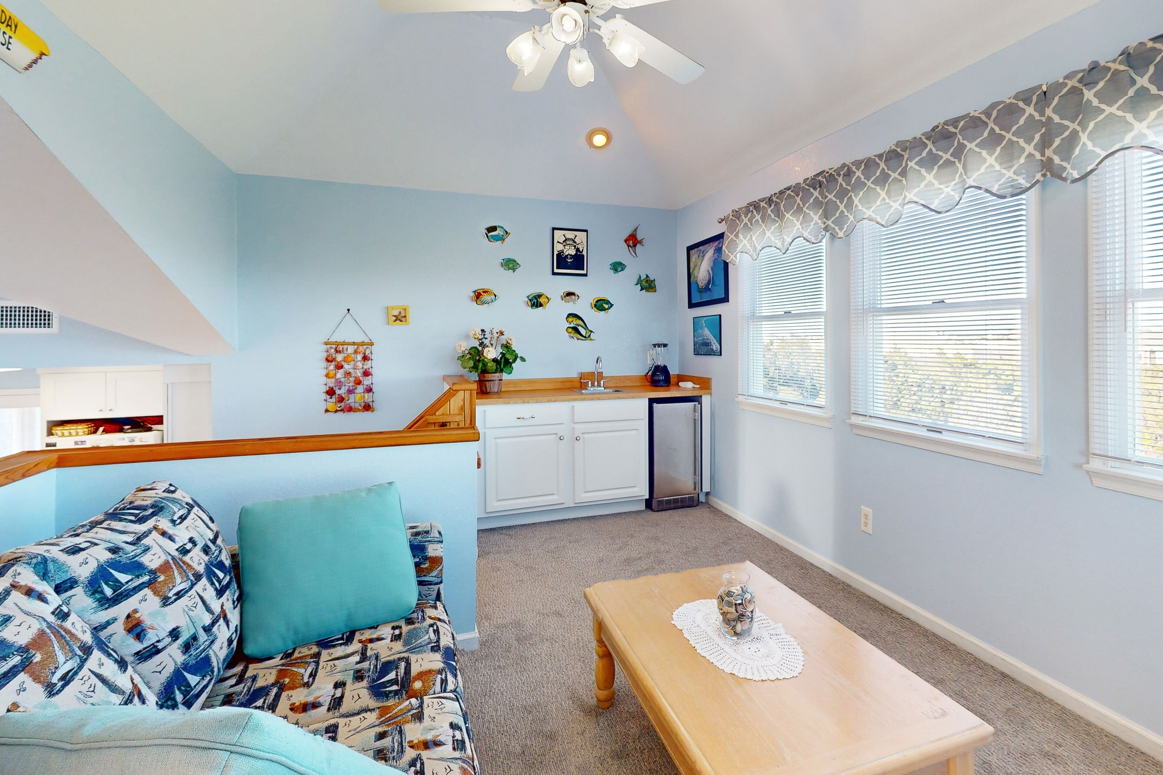 A living room with a sofa, a coffee table, and a kitchen area with cabinets and a refrigerator.