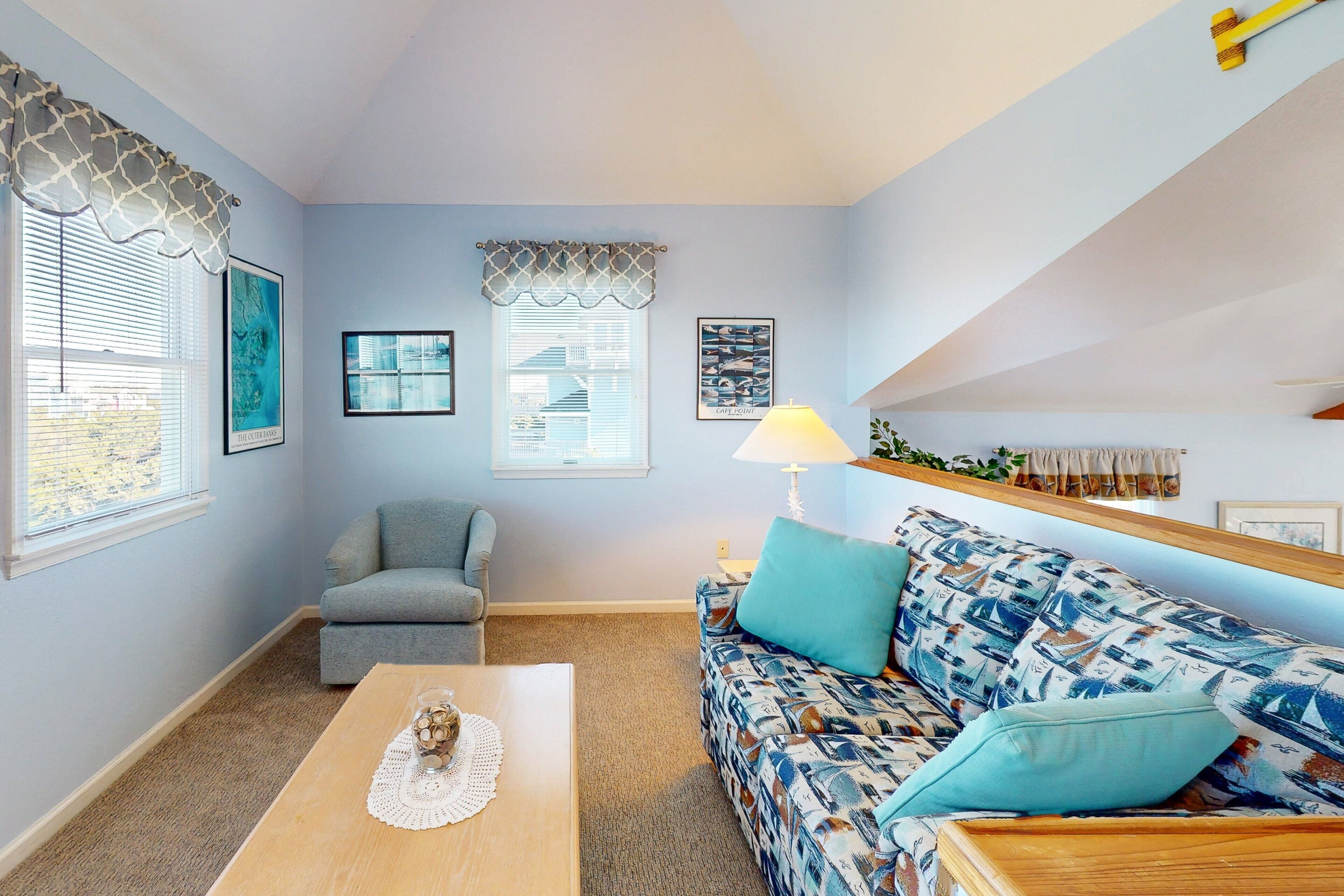 A living room with a sofa, a chair, a coffee table, and framed pictures on the wall.