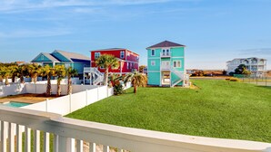 A residential area with colorful houses, a fenced yard, and a clear sky. - Condo near the beach with pool, BBQ area, balcony, & fireplace (Holden Beach)