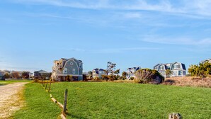 A residential area with houses and a grassy field. - Condo near the beach with pool, BBQ area, balcony, & fireplace (Holden Beach)