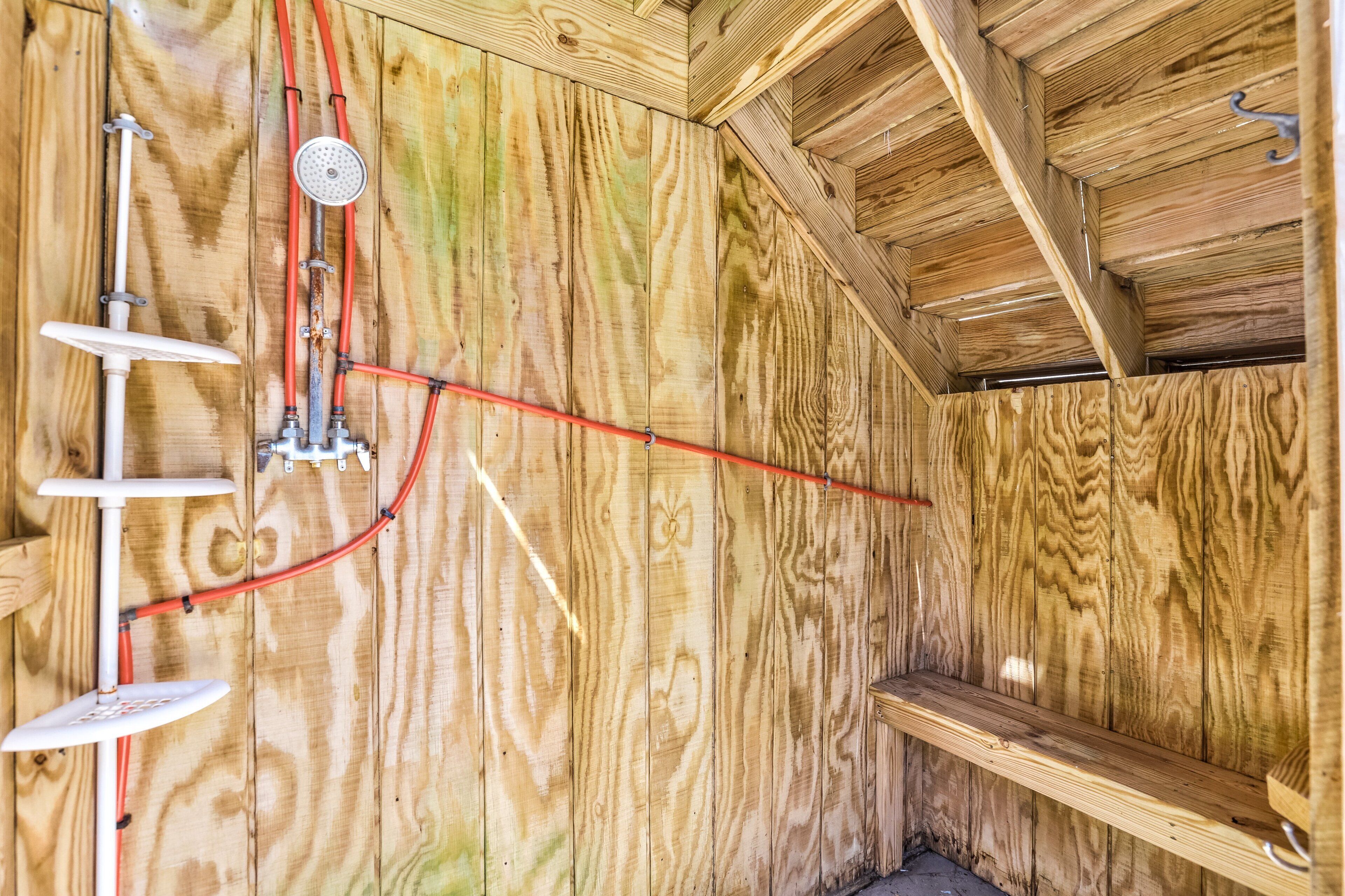 Un intérieur en bois avec un espace douche, comprenant des tuyaux et un pommeau de douche.