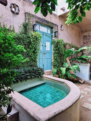 A courtyard with a blue door, a small pool, and lush greenery. - Casa Santorini: elegant stay next to La Ermita (Mérida)