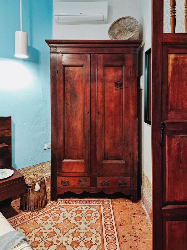 A room with a wooden wardrobe, a patterned rug, and a woven basket on the floor. - Casa Santorini: elegant stay next to La Ermita (Mérida)