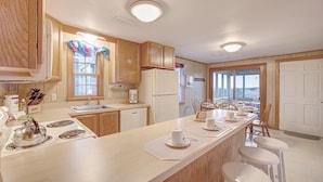 Une cuisine avec des meubles de rangement en bois, une cuisinière, un évier et un coin repas comprenant des chaises et une table.