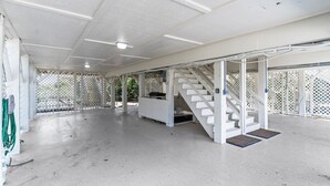 Zona interior àmplia amb una escala blanca, un espai de seients cobert i un sòl de formigó.