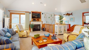 A living room with a fireplace, sofas, a television, and decorative items. - Semi-oceanfront house with private pool, hot tub, & ocean views (Avon)