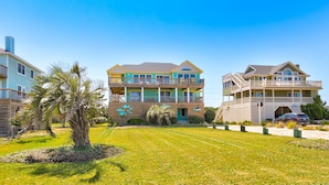 A multi-story residential building with balconies, a well-maintained lawn, and a clear blue sky. - Semi-oceanfront house with private pool, hot tub, & ocean views (Avon)