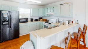 Une cuisine moderne avec des meubles de couleur bleu clair, un réfrigérateur noir, un four à micro-ondes, une cuisinière et un évier.