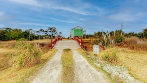 Un chemin de terre mène à un bâtiment vert sur lequel passe un pont rouge.