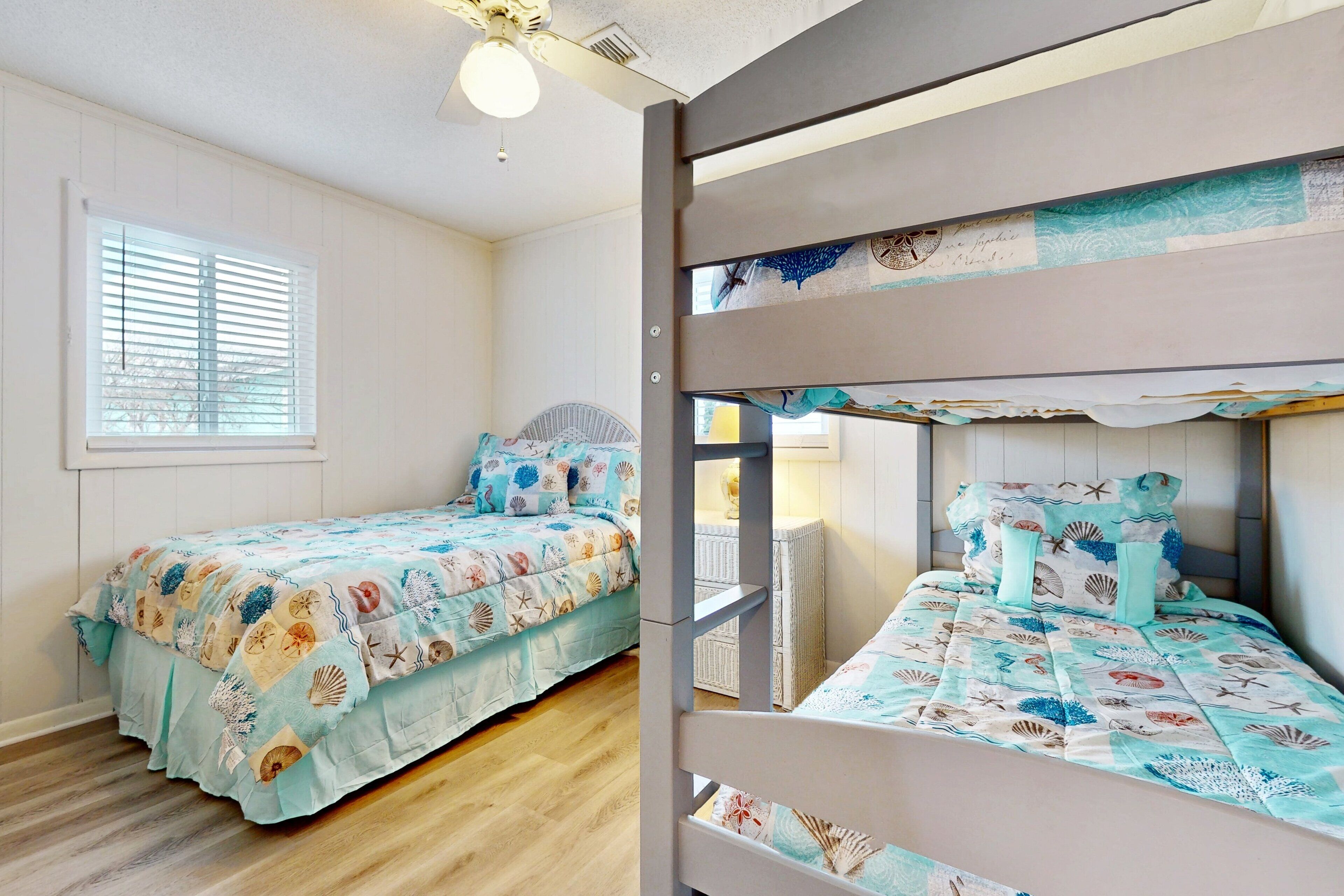 A room with bunk beds, a window with blinds, and a ceiling fan.