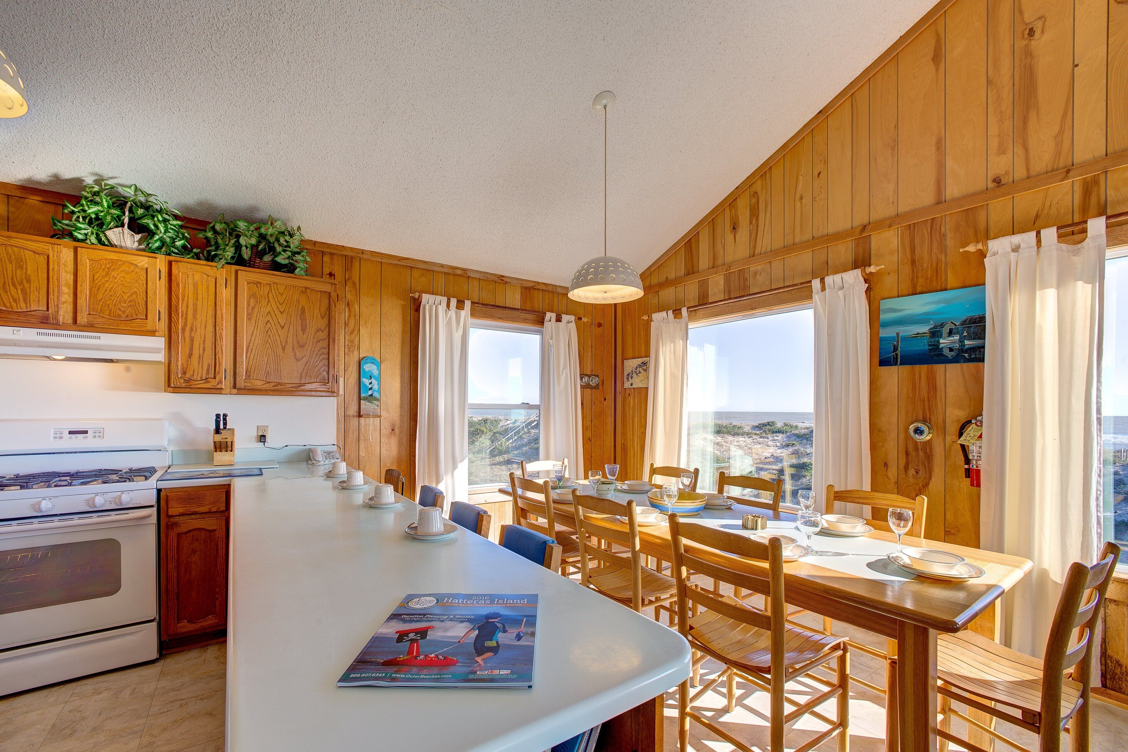 A kitchen with wooden cabinets, a white stove, and a dining area with a table set for two.