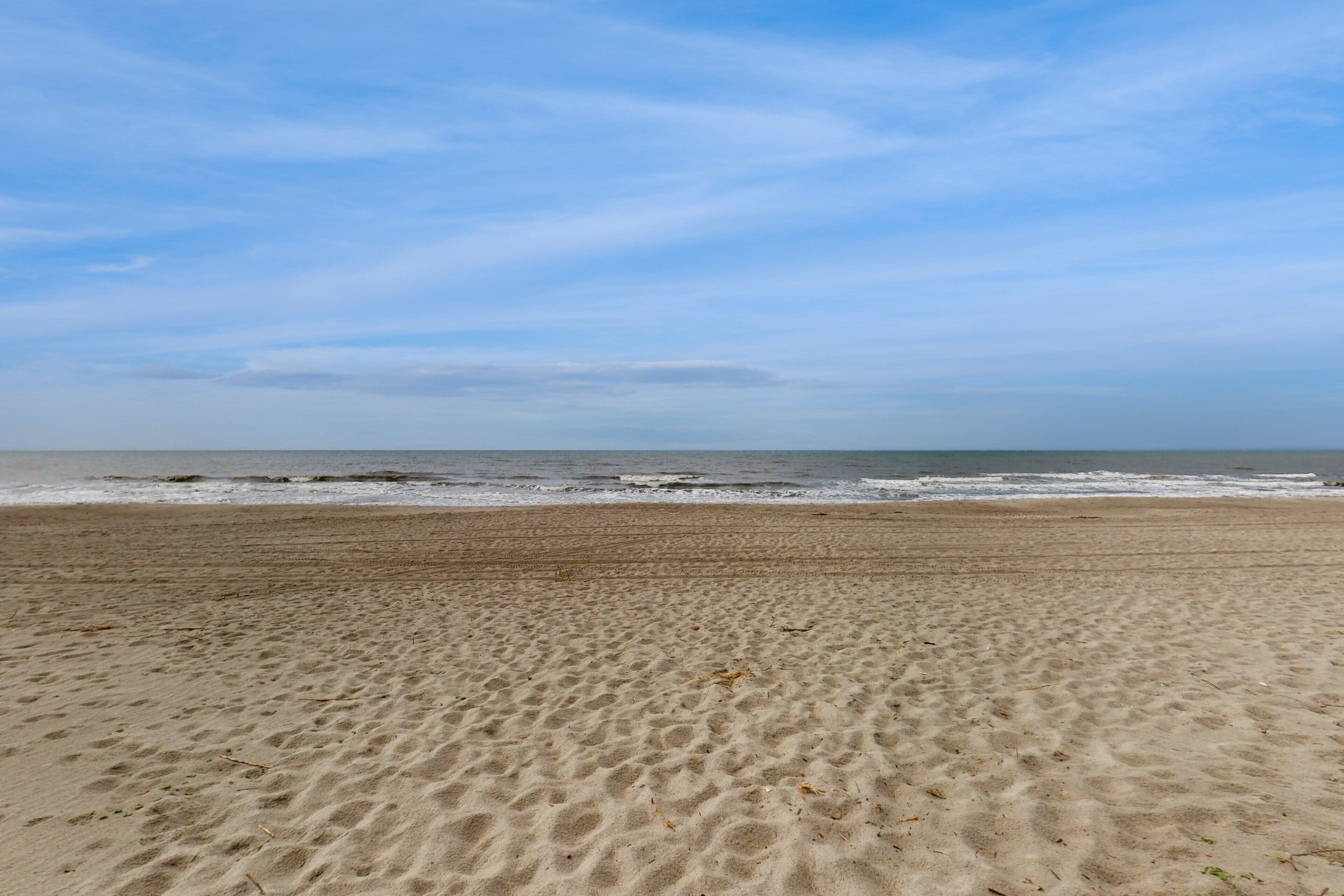 A sandy beach with gentle waves and a clear sky.