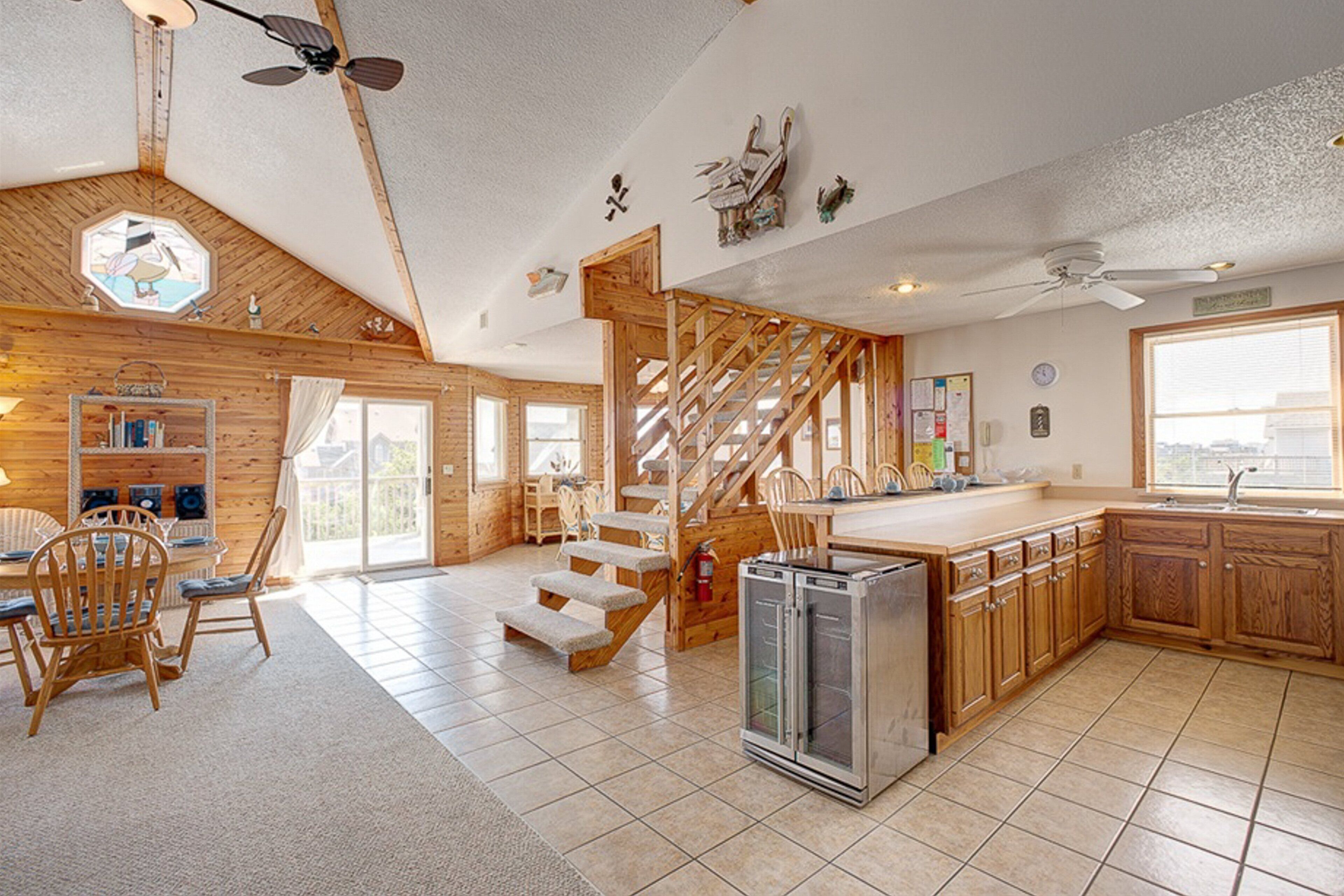 A spacious kitchen with wooden cabinets, a refrigerator, and a dining area with chairs and a table.