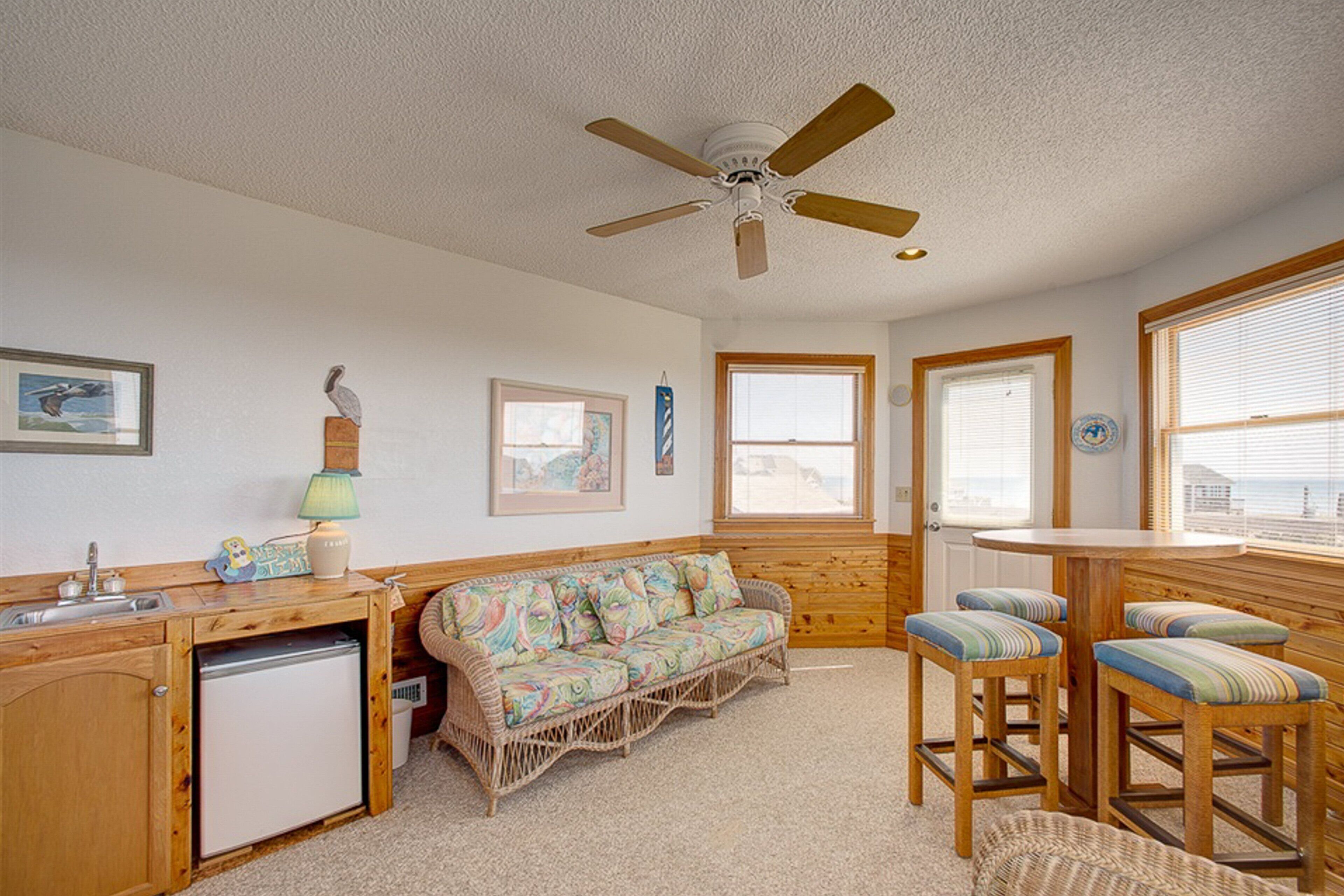A compact kitchen with a refrigerator, wooden counter, and a ceiling fan.