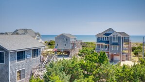 Une propriété située en bord de mer, comprenant plusieurs maisons, notamment un bâtiment à deux étages doté d’un balcon et une maison plus petite avec une terrasse.
